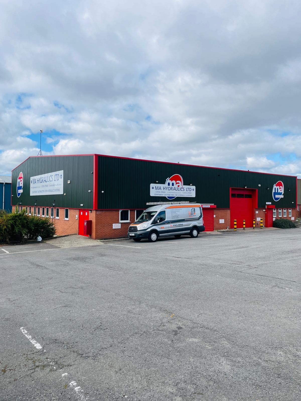 Commercial cladding spraying: industrial unit resprayed jupiter green with red roller shutter doors and trims